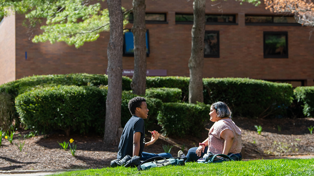 two people side outdoors on grass talking