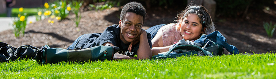 2 students lying down on the grass