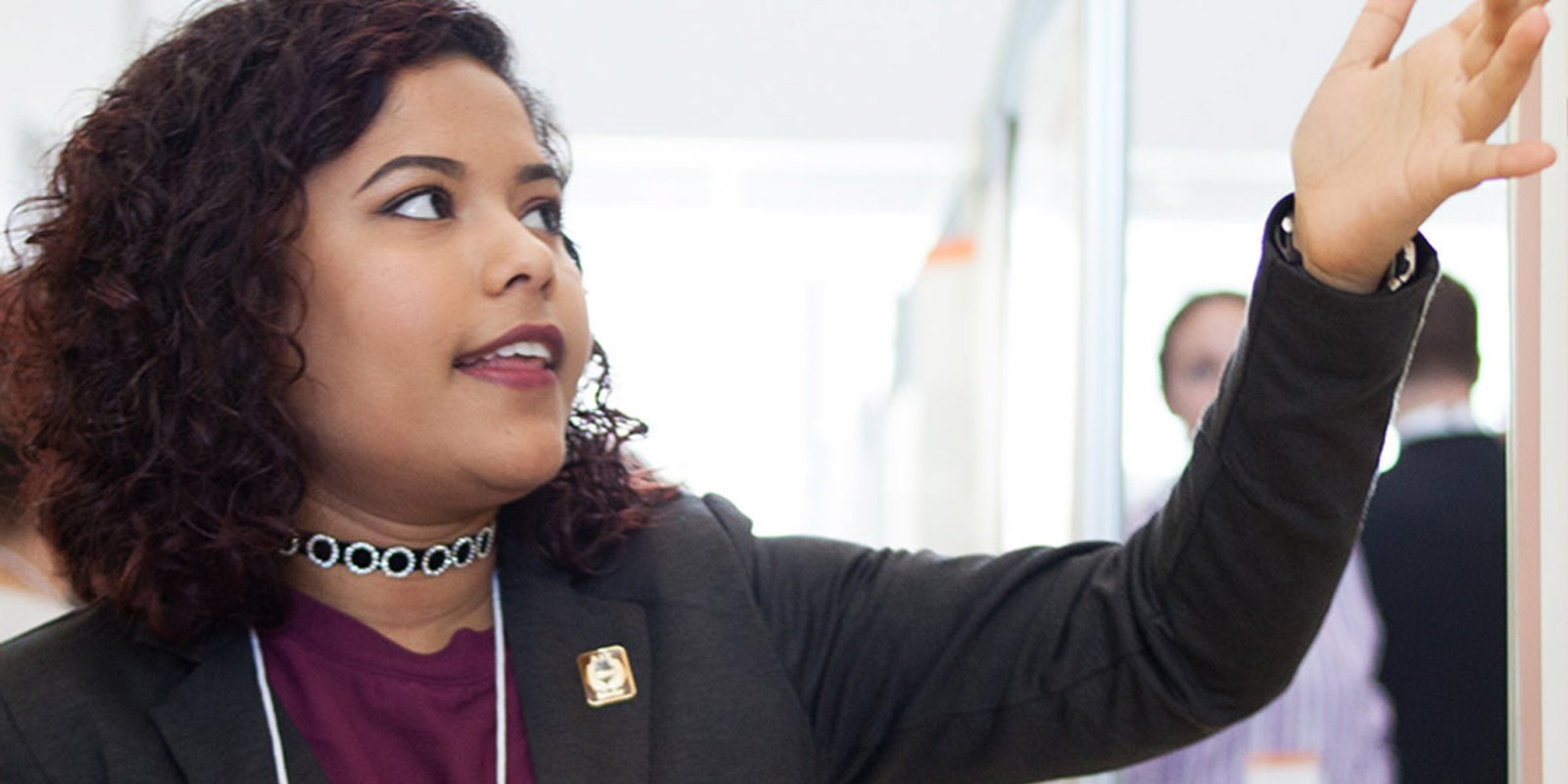 A woman in an office pointing to a whiteboard, engaged in a discussion or presentation