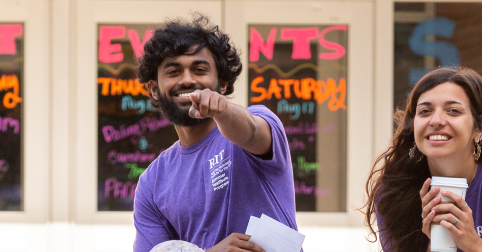 student smiling and pointing right at the camera