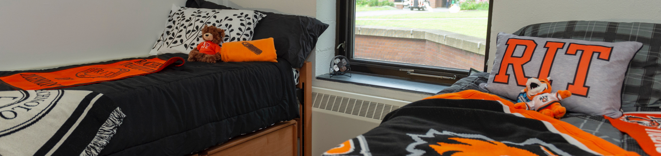 Two beds in a residence hall adorned with RIT apparel 