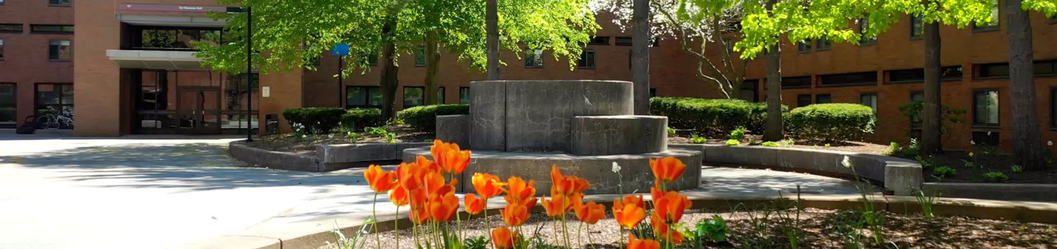 courtyard in middle of residence halls with stone sculpture and flowers