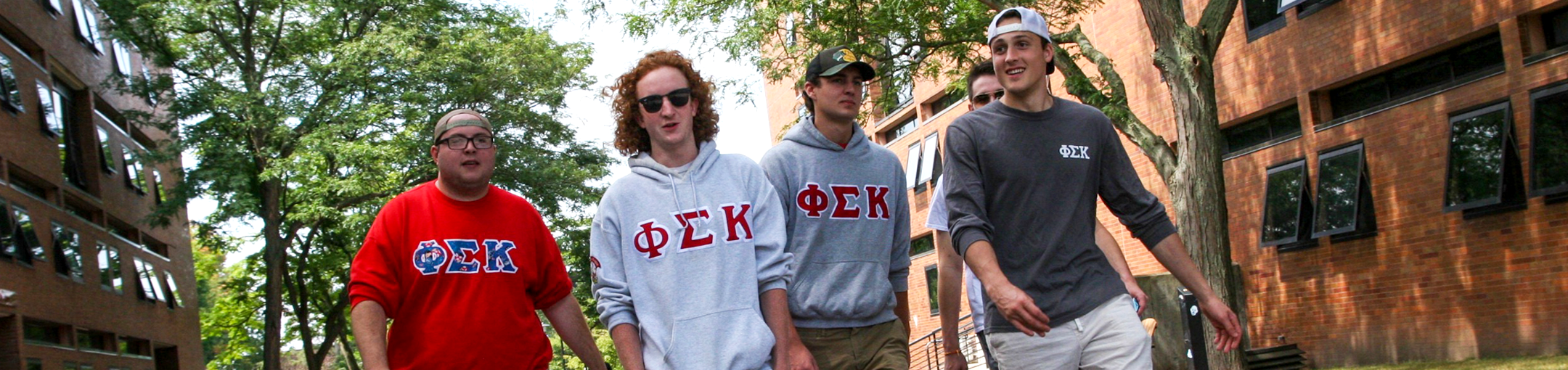 four students walking outside with greek sweatshirts on