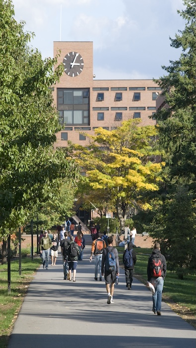 Kate gleason hall clock with trees and students walking