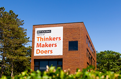 brick building with a banner on it saying "Home of Thinkers, Makers, Doers"