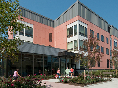 three story brick building with landscaping and people walking