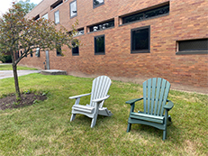 two adirondack chairs in front of brick residence hall C