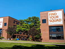 two brick buildings with banners on them saying Home of Thinkers, Makers, Doers