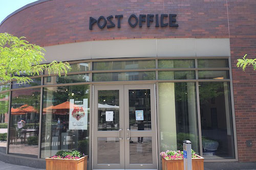exterior of a brick building with the sign "post office" above the doors