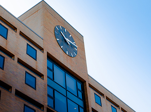 top of a high rise brick building with a large black clock at the top