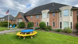 exterior of Greek Circle brick residence with a flag pole and round picnic table outside