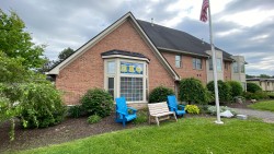 exterior of Greek Circle brick residence with a flag pole and Adirondack chairs outside