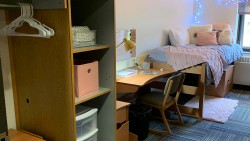 twin bed with a comforter, desk, cubbies, and closet