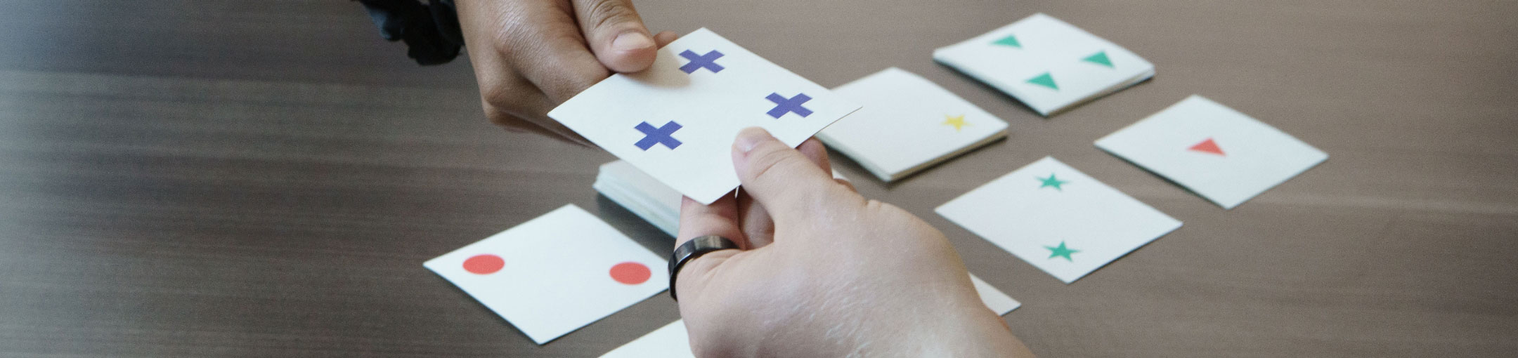 A closeup of two hands holding a flashcard with three plus signs on it.