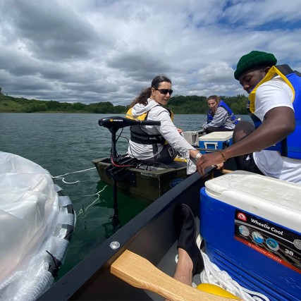 three researchers on a boat in a lake.