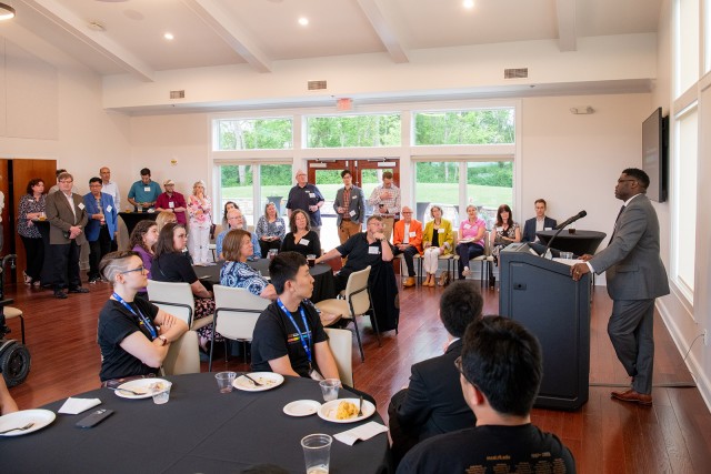 group of people standing and sitting in a meeting room listening to a presenter.