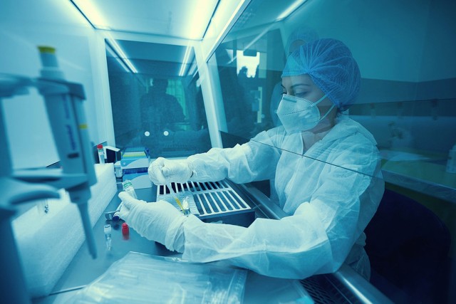 person wearing clean room protection and working with a pipette.