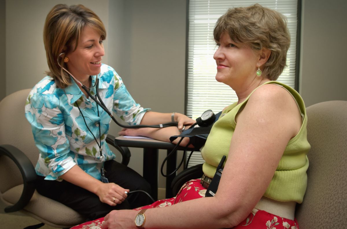 doctor checks blood pressure for patient sitting in a chair