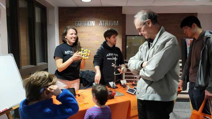 Exhibitors show a physical crystal model to visitors of many ages