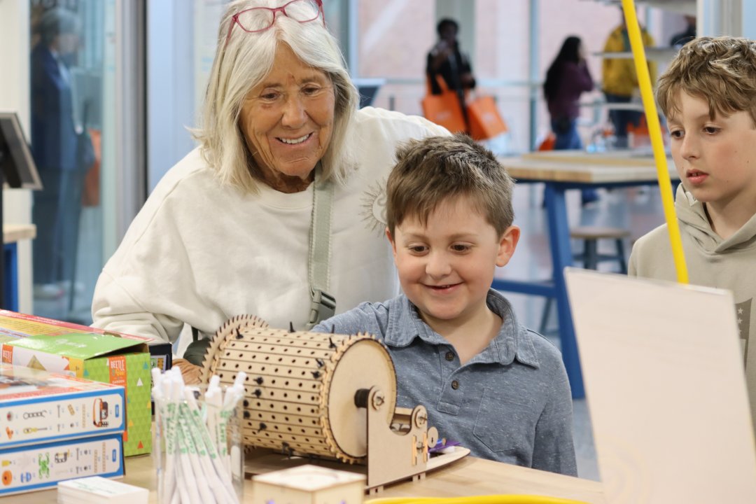 A mother and son playing with a computer that makes music.