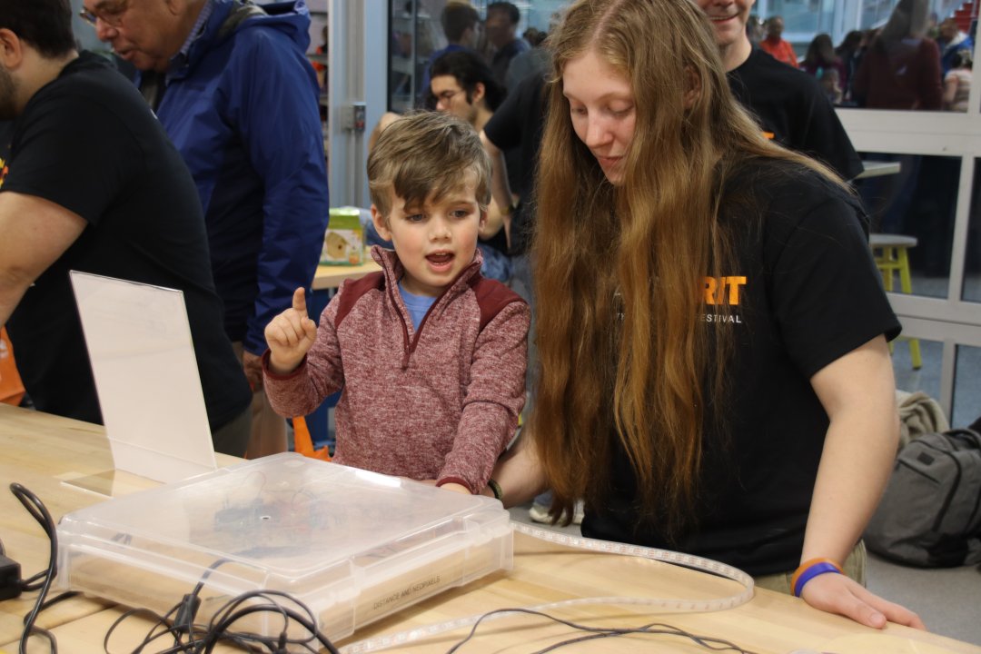 Child playing with a micro-computer, working with an RIT student.