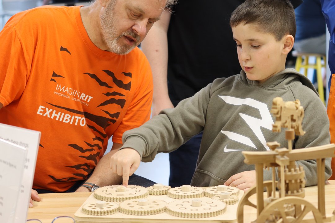 Dr. Thomas B. Kinsman and a guest playing with a pile of interconnected gears.