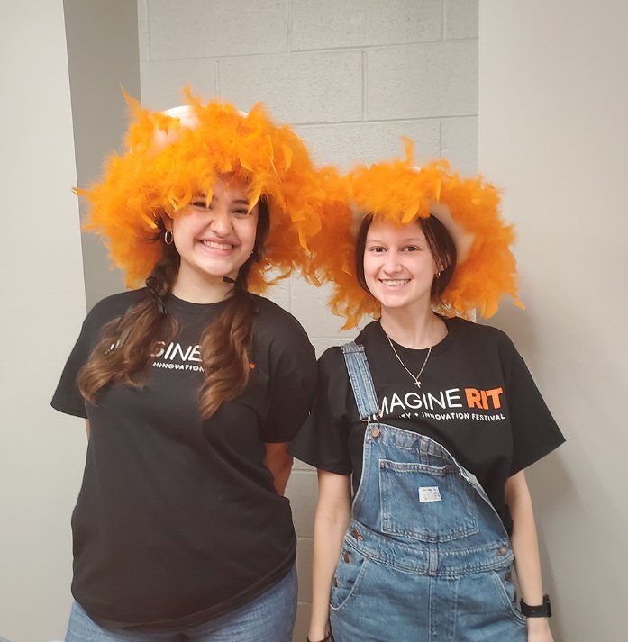 Two presenters wearing silly orange feathered hats