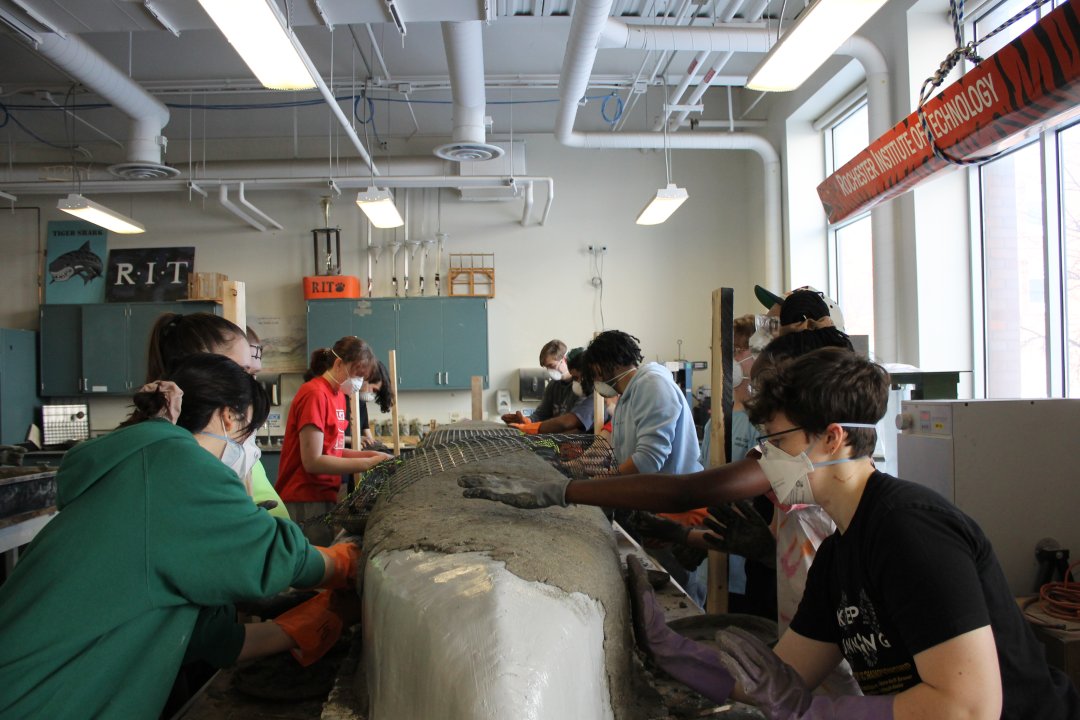 Members gathered around the canoe placing a layer of mesh on top.