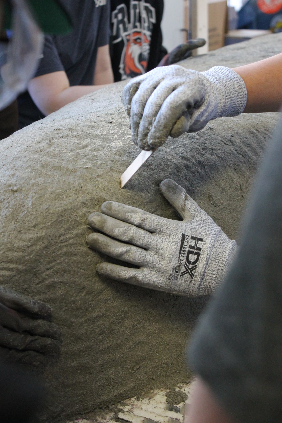 A person using a depth checker in the first layer of concrete.