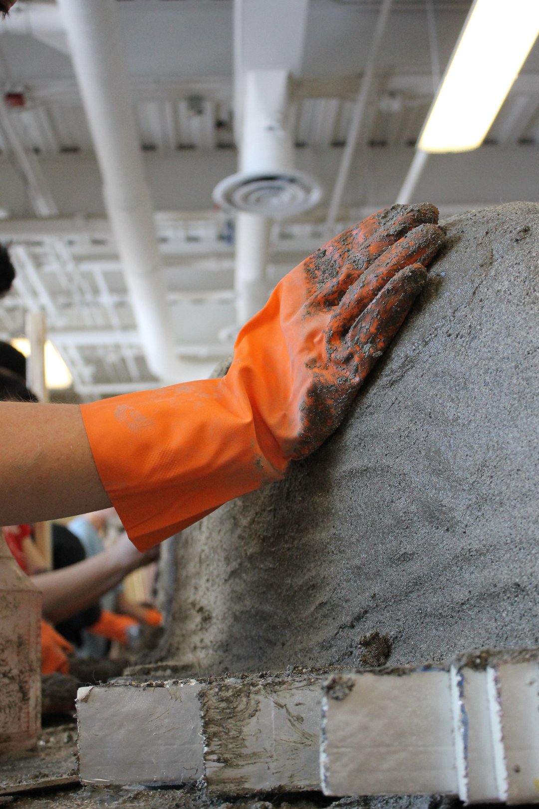 A gloved hand pressing concrete into the canoe.