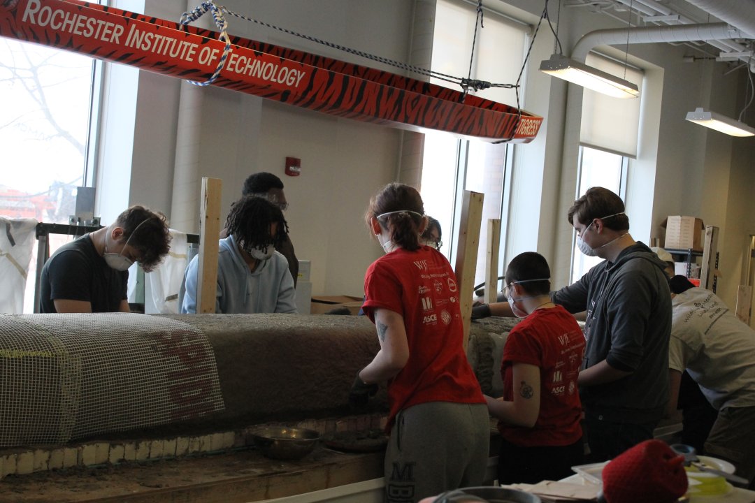 Members gathered around the canoe placing concrete.