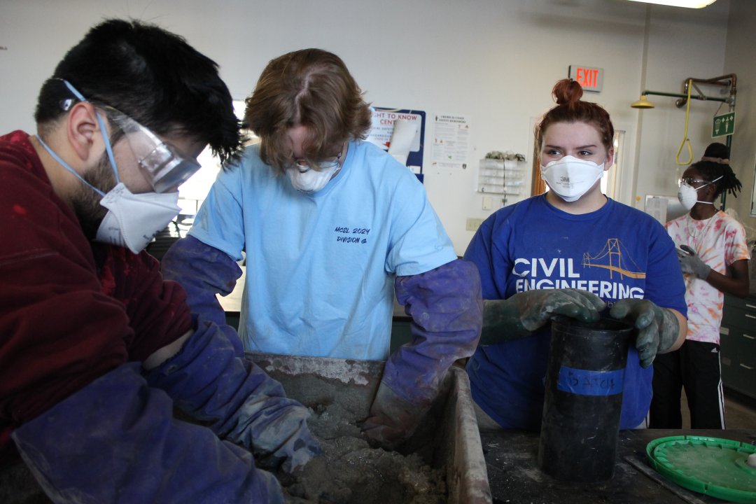 Two people hand mixing a batch of concrete.