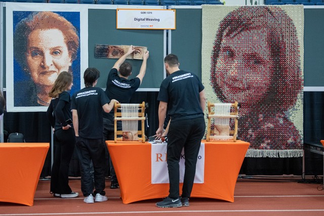 college students hanging up tapestries with portraits woven onto them.