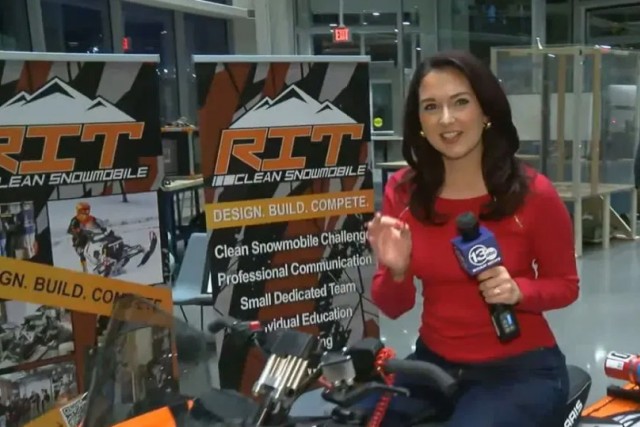 a news reporter sits on an R I T clean snowmobile that is on display at Imagine R I T.