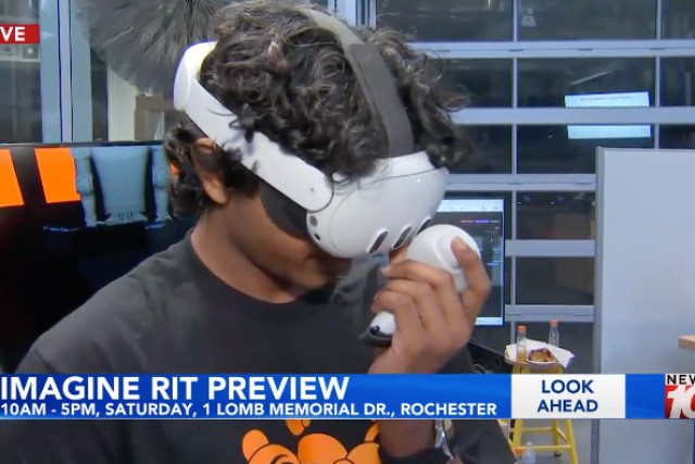 a student wears a V R helmet in the atrium of a building at R I T
