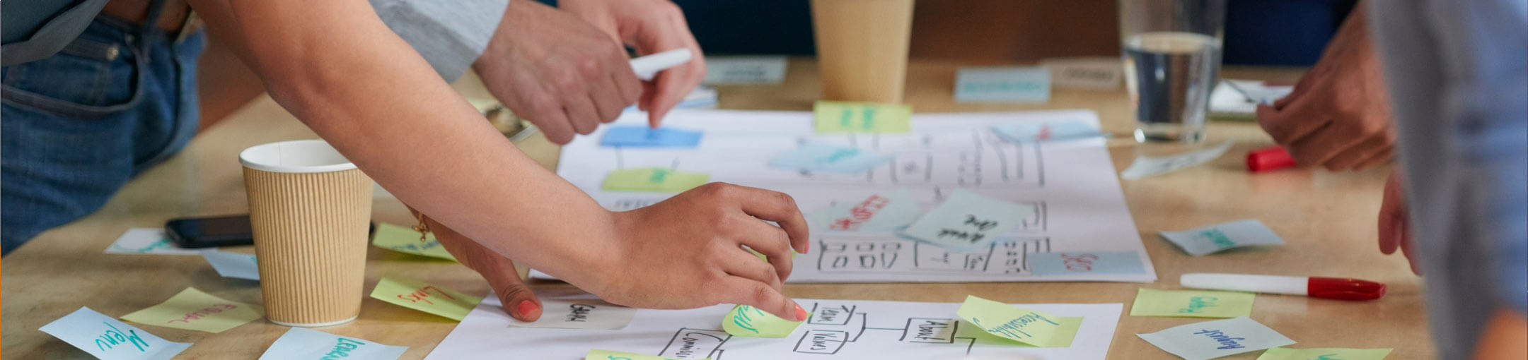 A close up of people's hands working on charts on a table.