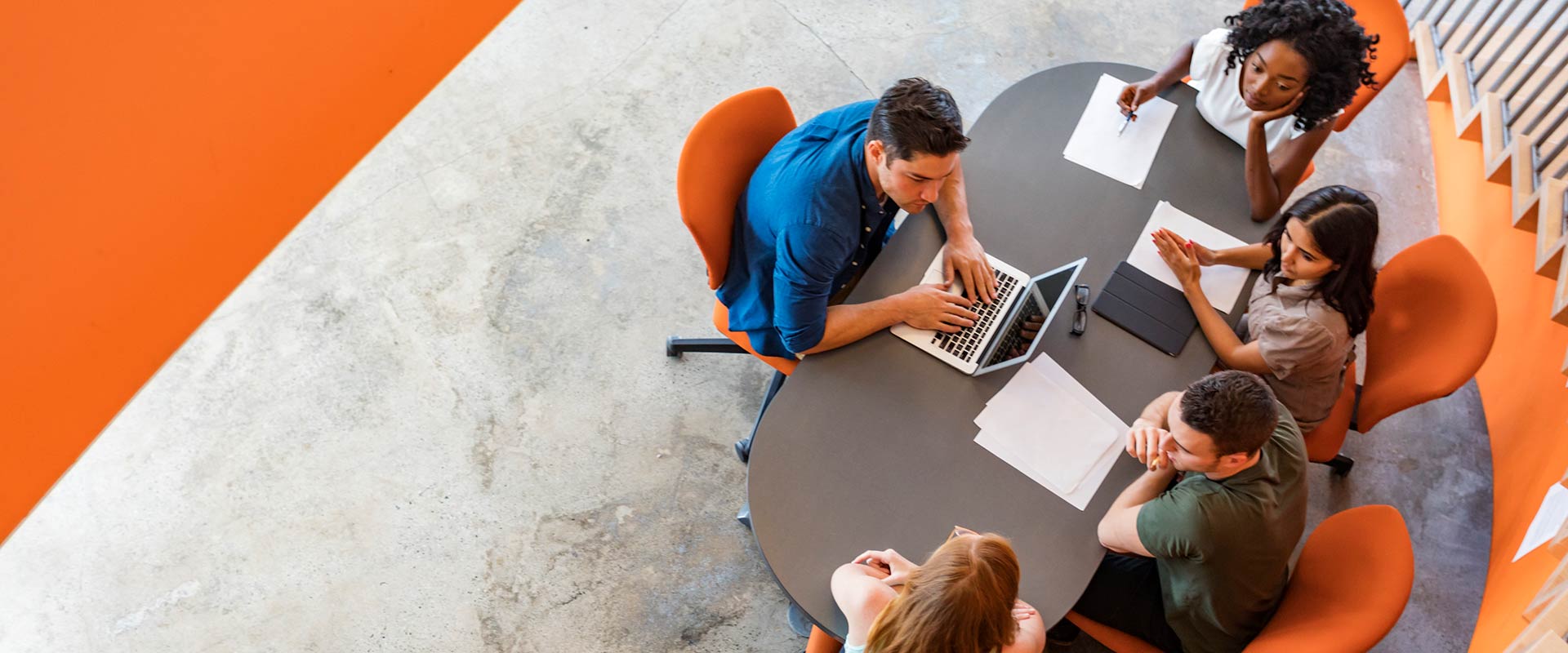 Overhead view of four people sitting at a table, having a meeting.
