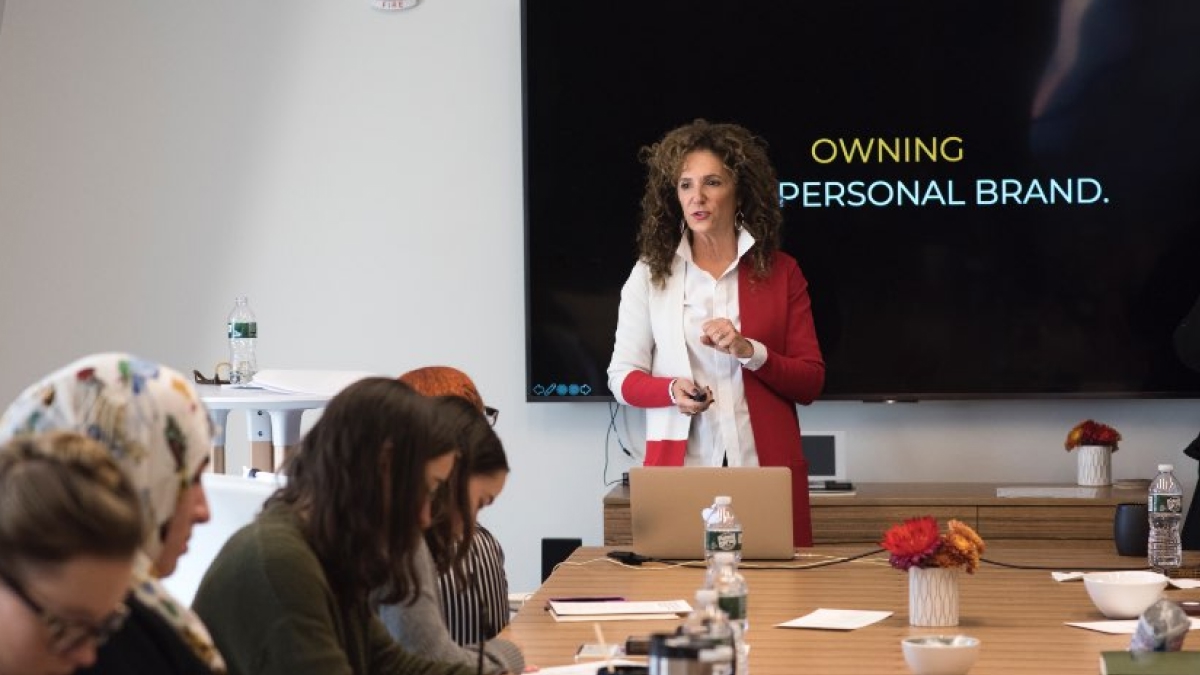 Sharon Napier speaking to a group of students during The Napier Experience workshop at RIT, with a screen behind her displaying the words 'Owning Personal Brand.'