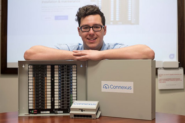 Brandon Hudson standing behind his thermostat system.