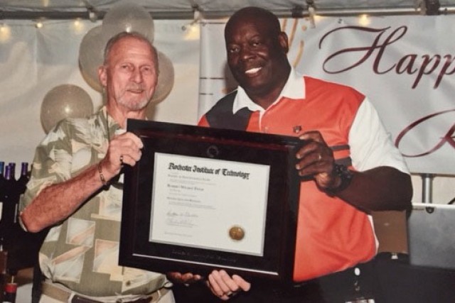 Two older people holding a degree from RIT.