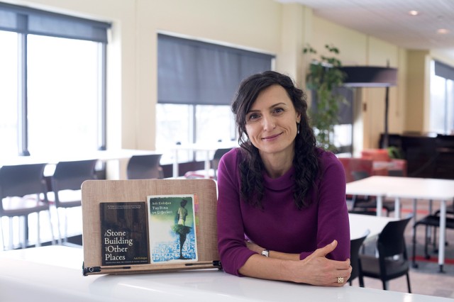 Woman sits at table with two books propped up on easel