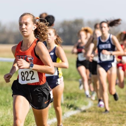 group of track and field student athletes running outdoors.