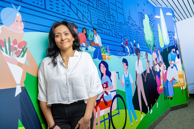 Maricela Marquez standing in front of a wall with a mural.