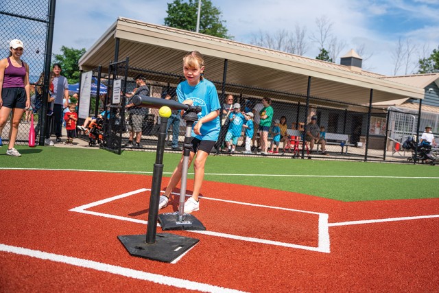 girl swinging a baseball bat mounted to a pole.
