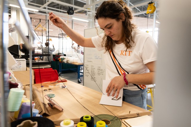 A student binds a book in the textile makerspace in the SHED.