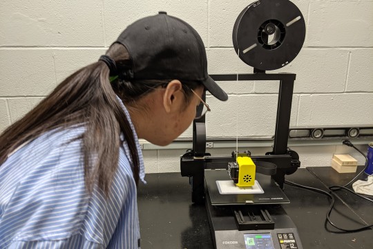 Xinxin Li observes a 3D printer in action.