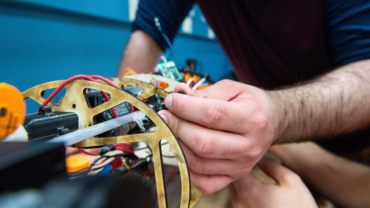 closeup of a person working on the wiring for a robotic fish.
