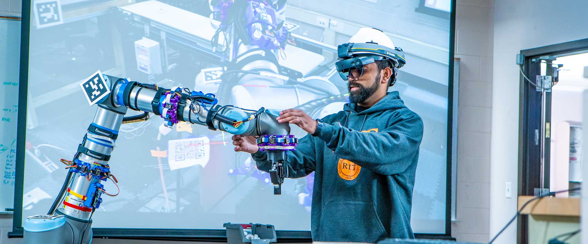 a college student wearing V R goggles adjusts a robotic arm.