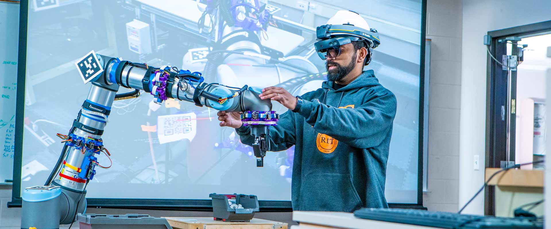 a college student wearing V R goggles adjusts a robotic arm.