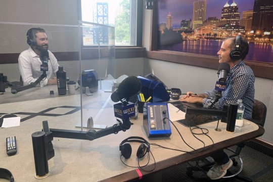 two people talking in a radio station sound booth.